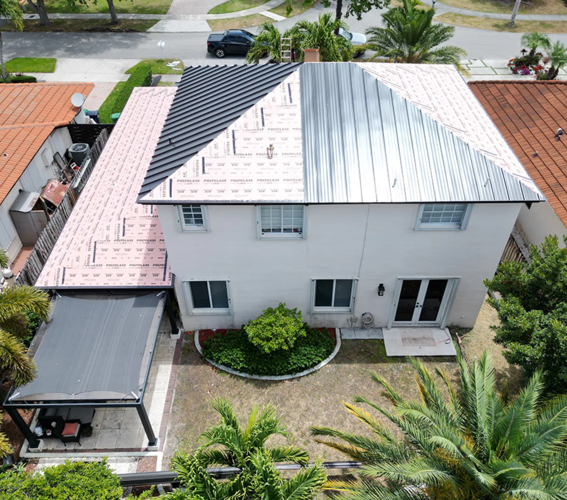 Titan crew mid-install on a standing-seam metal roof - underlayment and panels going down